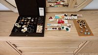 Overview of costume jewelry collection including earrings, brooches, and bracelets displayed in a box and on a surface
