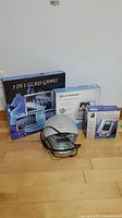Full lot with all items including 3-in-1 glass games set in box, Electrohome photo frame box, Innovage phone box, and Koss clock radio with cables.