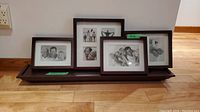 Four wooden picture frames with black and white photos displayed on floating shelf, showing overall lot contents