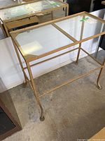 Full view of metal and glass top side table in garage setting on concrete floor.
