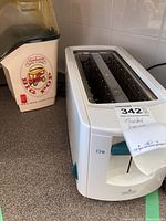 Photo showing Philips white toaster with super wide slots beside Sunbeam Big Pop popcorn maker with red vintage style logo