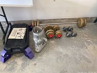 Wide shot showing the black step platform with purple risers, gray stabilizing boot, barbell and dumbbells with gold-colored weights.