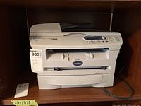 Front view of Brother DCP 7020 multifunction laser printer/copier/scanner showing the main body with power cord and paper tray.