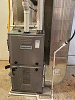 Full view of Comfortmaker furnace with PVC intake and exhaust piping and duct connection