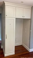 Front view of white kitchen cabinet set showing tall side cabinet and fridge opening