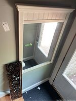 Carved wood wall decoration with intricate leaf and swirl designs, placed below the mirror for scale.