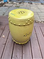 Full view of yellow glazed ceramic outdoor stool showing decorative nodules and pierced pattern.