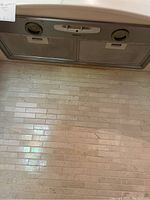 Top-down view of the Braun silver vent hood mounted under a kitchen cabinet, showing two metal mesh filters.