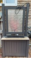 Front view of dark wood planter stand with metal screen trellis insert and window box planter on top, attached cord visible.
