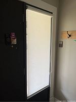 Full view of a white roller blind installed inside a window frame, partially drawn down with bead chain control visible.