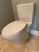 Side view of white Toto toilet showing long seat and makeup of the bowl and tank with polished finish.
