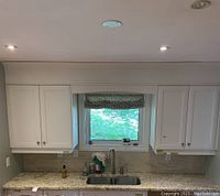 Front view of two white upper cabinets flanking a window above sink