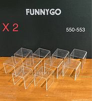 20 clear acrylic display risers arranged in two rows on wooden surface with Funnygo branding in background.