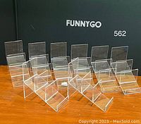 Seven clear acrylic display risers arranged in three rows showing different sizes and stepped design for display.