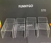Eight clear acrylic display risers arranged in two rows of four units each, on a flat surface with a black backdrop labeled FUNNYGO.
