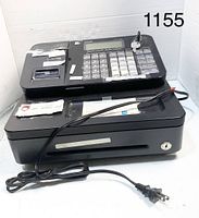 Front angled view of the used Casio PCR-T295 cash register showing the keypad, display area, cash drawer with lock and the attached power cord.
