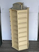 Front angle view of beige rotating countertop display unit showing multiple slots and 'Rachel' top sign.