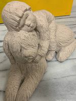 Off-white textured sculpture showing a small boy lying on a shaggy dog, side view focusing on the boy's peaceful facial expression and embracing pose.