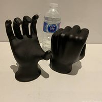 Photo showing two black vintage hand figures side by side with a water bottle for size reference
