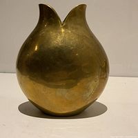 Front view of the round brass vase with double spout top showing patina and wear.
