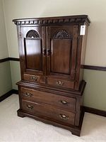 Front view of the Thomas P. Beals wooden armoire showing the detailed upper cabinet doors and drawers below.