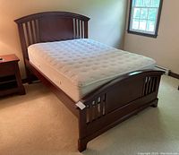 Angled front-left view of the bed showing the headboard, mattress, and carpeted floor.