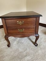 Front view of the cherry wood end table showing two drawers with brass handles, cabriole legs, and scalloped apron base.