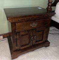 Front view of Thomas P. Beals wooden nightstand showcasing drawer and cabinet with brass and metal hardware.