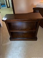 Wooden bookcase front view showing the entire piece with one middle shelf and base molding.