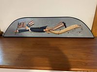 Side view of hand painted 4th of July wooden wall plaque on wooden surface.