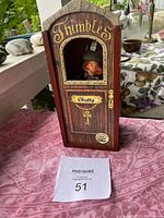 Front view of wooden case with visible doll inside, labeled 'Thimbles Chatty'.