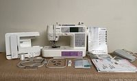 Full set of the Brother SE-400 machine with embroidery hoops, presser feet, manuals, software CD, foot pedal, USB cord, and bobbins, shown on a brown surface.