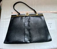 Front view of black genuine lizard skin purse with top handle and gold-tone clasp, measuring approximately 10.5 x 7.5 inches