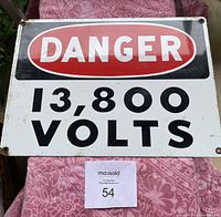 Front view of metal danger sign with text 'DANGER 13,800 VOLTS' on black, red, and white background.