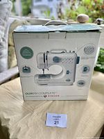 Front of the box showing Singer QuikFix Complete mending sewing machine with various features highlighted.