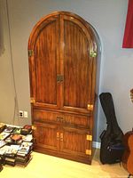 Front view of full wooden cabinet showing arched top doors and lower compartment closed