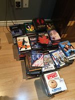 Photo showing a pile of DVDs on floor with visible DVD cover titles and bands like AC/DC.
