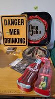 View of all items showing metal signs, rings in display case, Coca-Cola Lip Smacker tin, Twilight pin set