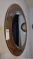 Angled side view showing the 32-inch round mirror with brownish mirrored mosaic edging in a cracked pattern texture.