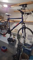 Full view of navy blue Norco mountain bike hung in garage, showing frame, wheels and attached bottle holders