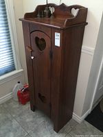 Full front view of the pine cabinet showing heart cutouts on door and top back panel with latch and key attached.