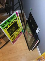 Photo showing two Bob Marley and The Wailers posters leaning against a wall and two framed album covers.