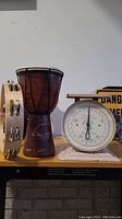 Front view of the nursery scale, tambourine and bongo drum together on table, showing scale's dial and the instruments' details.
