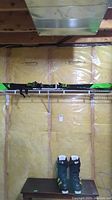 Rossignol skis mounted on shelf with Salomon ski boots on table beneath