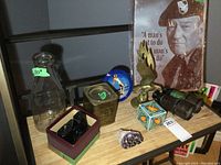 Overall lot displayed on wood shelf including quart size dairy bottle, blue View-Master, brass eagle figurine, old binoculars, metal gyroscope box, amethyst rock, and metal sign with a military man.