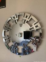 Full view of the round wall mirror showing the circular glass surrounded by a 3D geometric block frame mounted on a wall.
