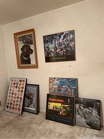 Room corner showing all six framed prints and posters arranged against wall, variety of styles and colors visible