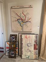 View of four framed art pieces including the DC Metro map and two opera history prints against wall and floor.