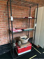 Front view of the black metal wire shelving unit filled with assorted household items for scale and condition reference.