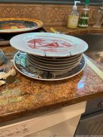 Stack of plates and platters on countertop showing red designs and black detailed border platter